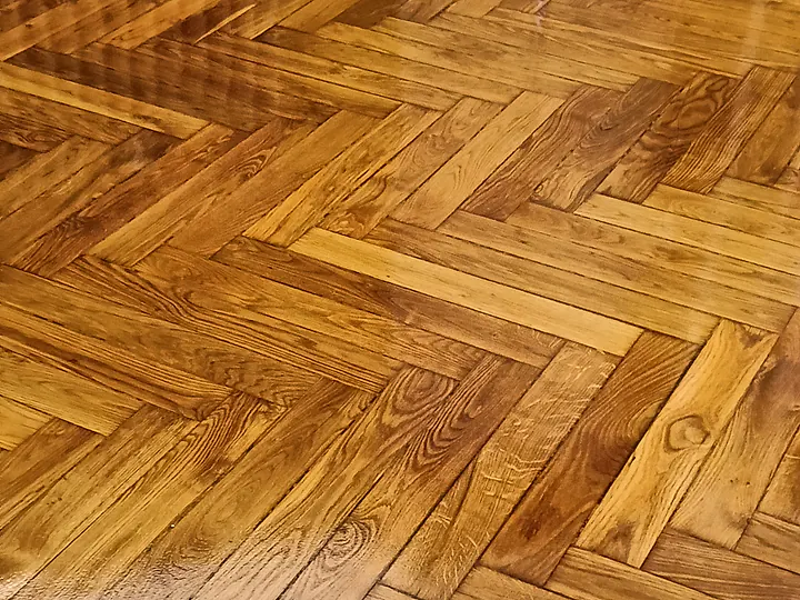 Antico parquet a spina italiana levigato e riverniciato, con la venatura del legno in evidenza sotto la finitura lucida