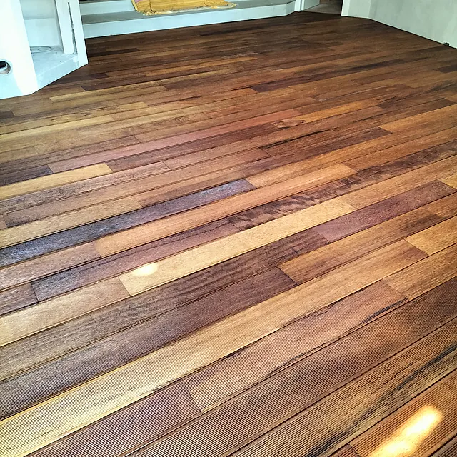 Decking in legno per esterno con doghe rigate posate a correre e fughe aperte, intorno alla vasca di una piscina