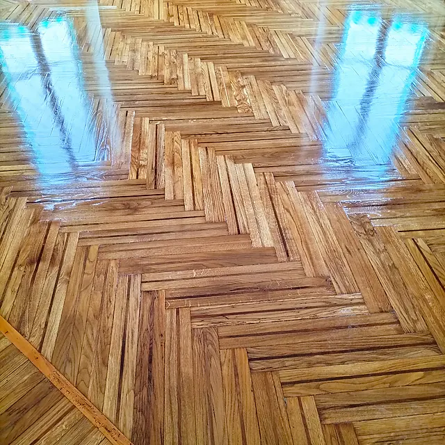 Antico parquet a spina italiana levigato e riverniciato a lucido, con i riflessi delle finestre sul pavimento