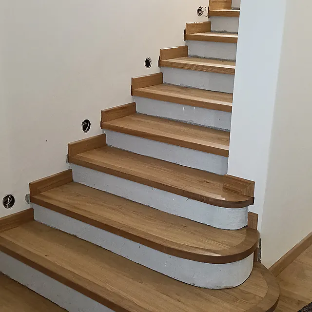 Scala interna con pedate in legno dal profilo arrotondato e alzate chiare